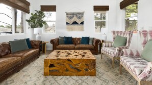 A living room with a brown leather sofa, a patterned armchair, a wooden coffee table, and a macrame wall hanging. - Mountain View with Hot Tub/AC nestled in the pines  (Flagstaff)