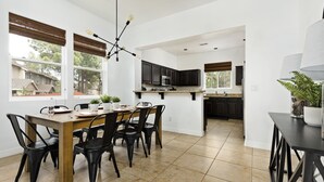A modern kitchen with dark cabinets, a wooden dining table, and black chairs. - Mountain View with Hot Tub/AC nestled in the pines  (Flagstaff)