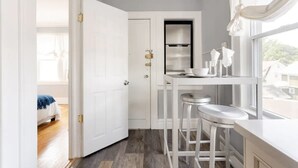 A narrow kitchen with white cabinetry, a stainless steel oven, and a window with a view of the outside.