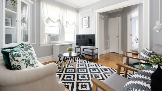 A living room with a sofa, a coffee table, a TV, and a patterned rug.