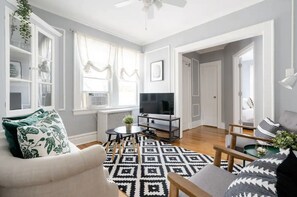 A living room with a sofa, a coffee table, a TV, and a patterned rug.