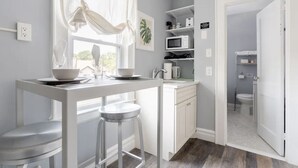 A compact kitchen with a dining area, white cabinetry, and a view to the outside.