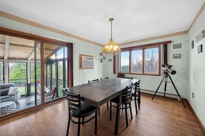 A dining area with a large table, chairs, a chandelier, and a telescope.