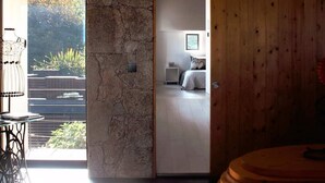 A modern interior with a stone wall, wooden paneling, a bed, and a view of greenery.