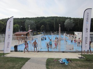 Ein Poolbereich mit mehreren Personen, einer umzäunten Liegefläche und Flaggen.