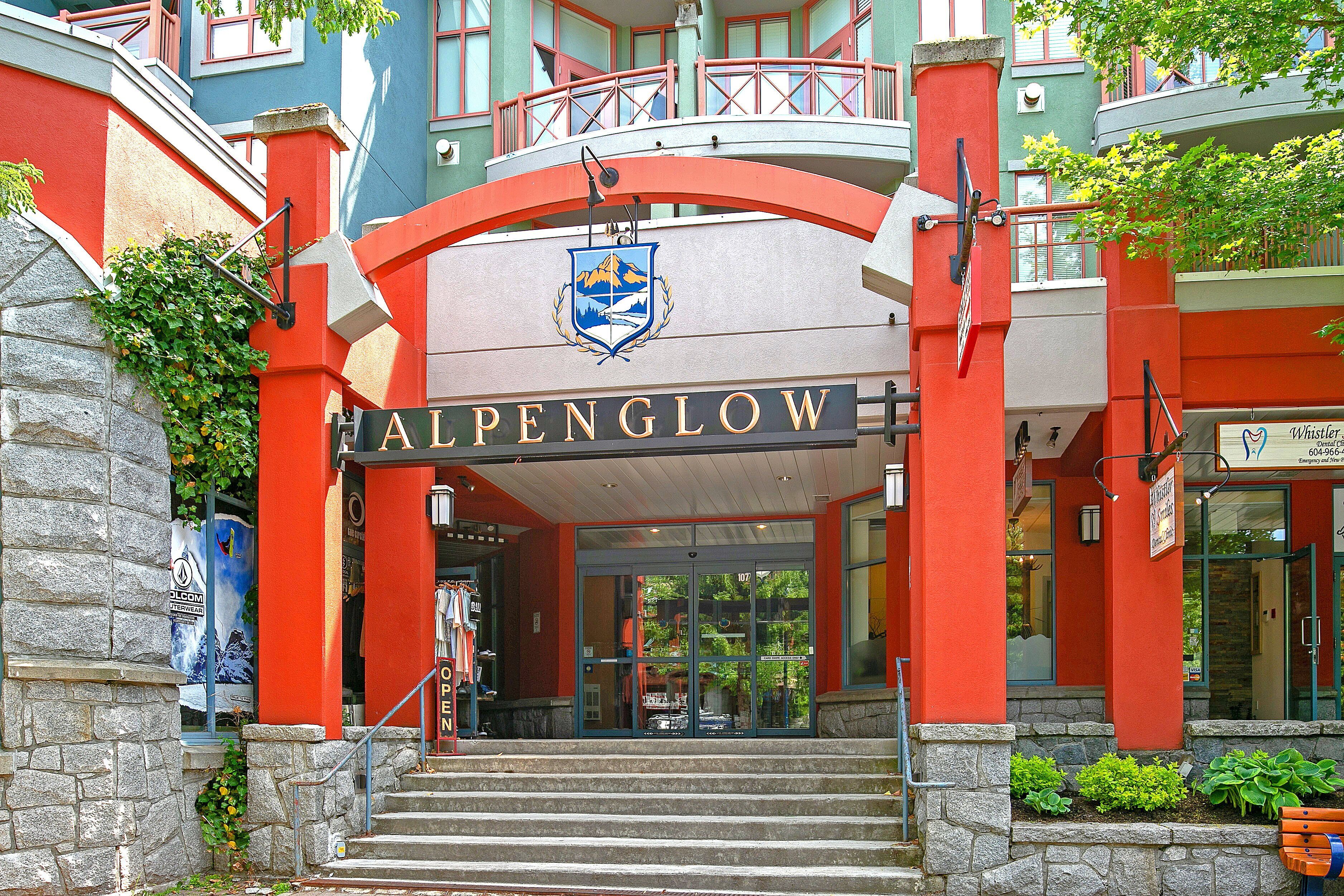 A building with a prominent 'ALPENGLOW' sign, stone steps leading to the entrance, and a balcony with a railing.