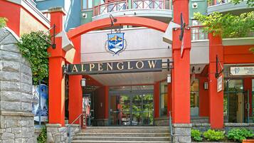 A building with a prominent 'ALPENGLOW' sign, stone steps leading to the entrance, and a balcony with a railing.