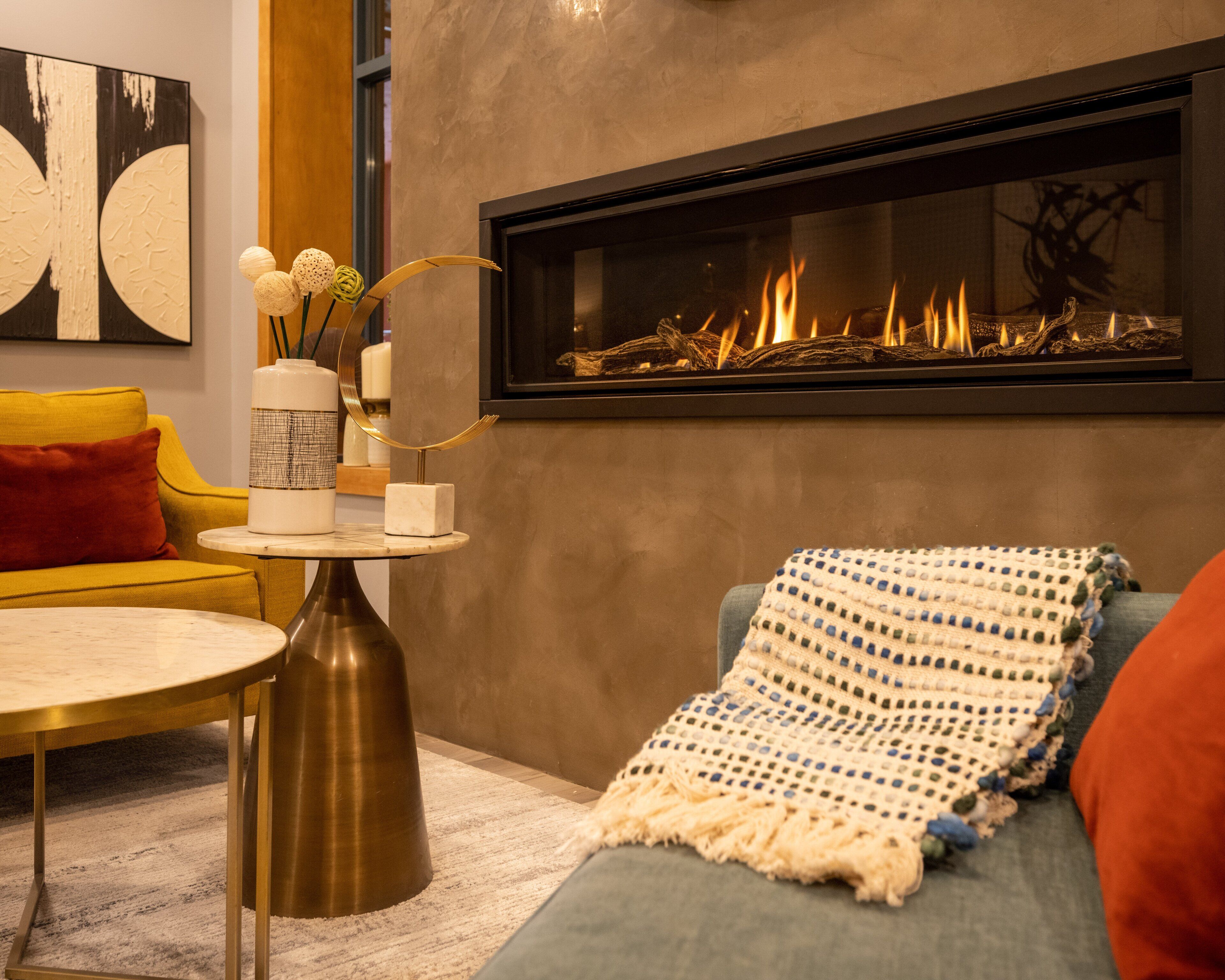 Ein modernes Wohnzimmer mit Kamin, einem gelben Sofa, einem runden Couchtisch und einer dekorativen Vase.