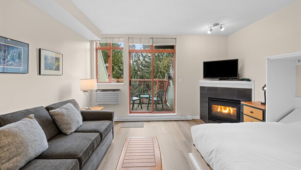 Een moderne slaapkamer met een bank, een bed, een televisie en een open haard.