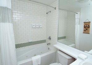 A bathroom with a bathtub, toilet, and sink, featuring white tiles and a checkered pattern at the base. - Alpenglow Lodge Legacy Studio by MVA (Whistler)