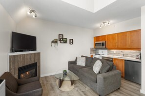 Uma sala de estar moderna com televisão de tela plana, lareira, sofá e mesa de centro de vidro.