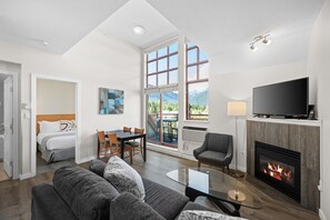 Uma sala de estar moderna com lareira, televisão e área de jantar com vista para montanhas.
