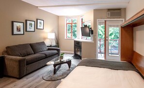 A modern room with a sofa, a bed, a TV, and a fireplace.