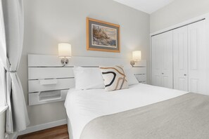A bedroom with a bed, bedside lamps, a nightstand, a wall-mounted shelf, and a wardrobe. - Junior One Bedroom Apartment at Whistler Village! (Whistler)