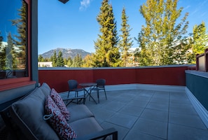 A balcony with a sofa, chairs, and a table.