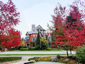 A large red building with a modern architectural style, surrounded by a well-maintained garden with red-leaved trees. - Alpenglow Lodge Large Studio with Dedicated Work Space by MVA (Whistler)