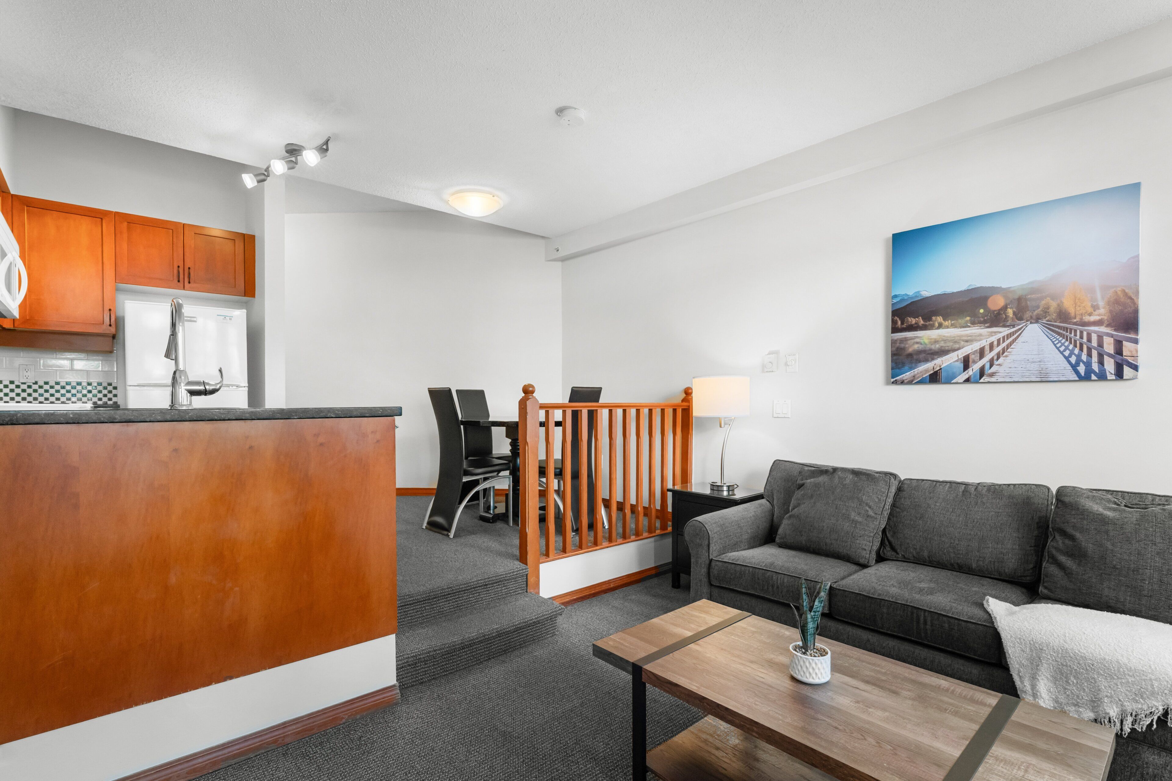 A modern living room with a sofa, coffee table, and a painting of a bridge.