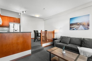 A modern living room with a sofa, coffee table, and a painting of a bridge.
