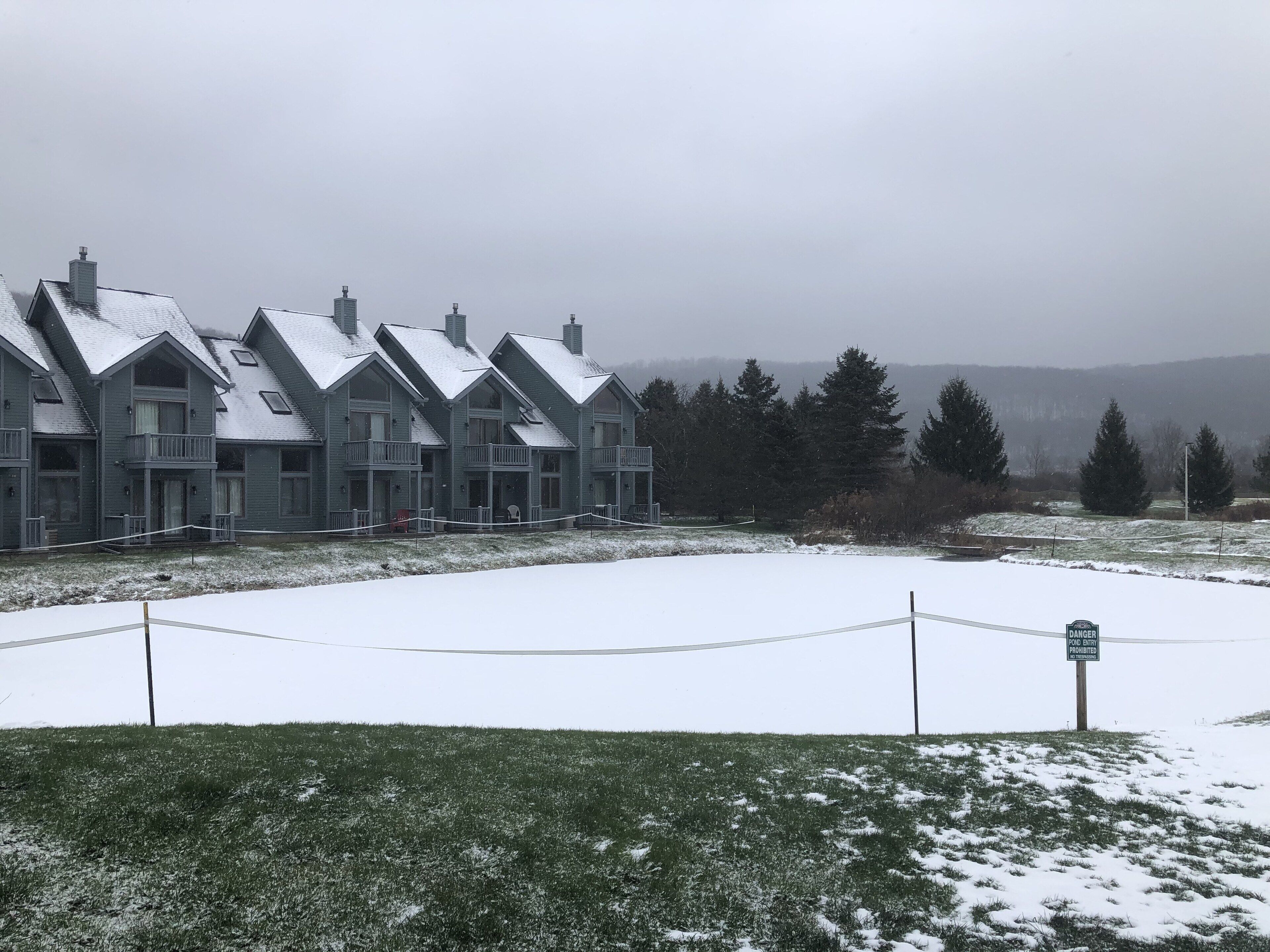 A row of multi-story buildings with a snow-covered lawn and a 'No Entry' sign.