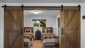 A bedroom with two beds, a window with a view, and a wooden floor.