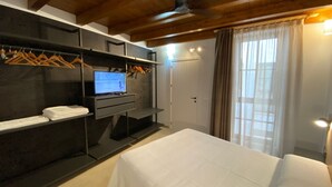 Ein Schlafzimmer mit einem Bett, einem Fernseher auf einem Schrank, einem Kleiderschrank und einer Tür.