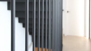 Eine moderne Treppe mit Metallgeländer und Holzhäuschen.