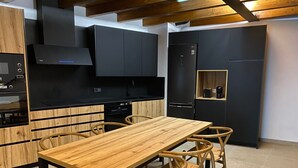 Eine moderne Küche mit Holztisch und -stühlen, eingebauten Geräten und minimalistischem Design.