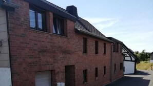 Ein zweistöckiges Backsteinhaus mit Garagentor, kleinem Fenster und einer Tür mit Briefkasten.