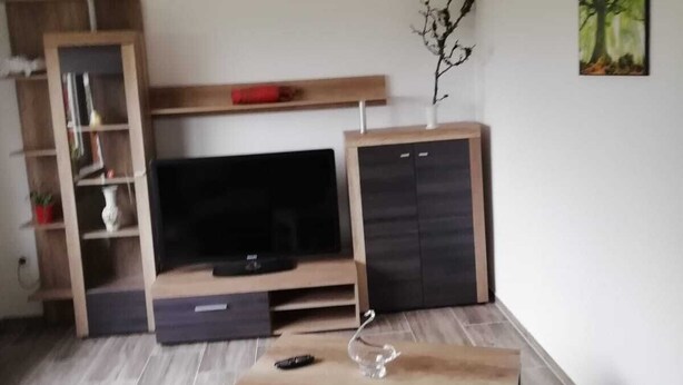 Ein Wohnzimmer mit Fernseher, Holzunterhaltungseinheit und einer Couch.