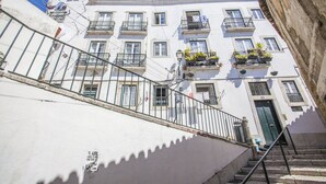 A multi-story building with balconies, a staircase, and a door.
