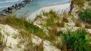 A beach with a rocky breakwater and sand dunes.