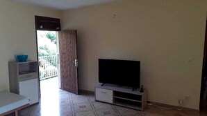Ein Zimmer mit Fernseher auf einem Schrank, einem weißen Korpus und einer Bank.