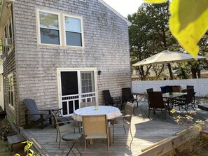 Enjoy outdoor dining or relaxation on the deck with table and chairs, surrounded by a picket fence and comfortable seating options.