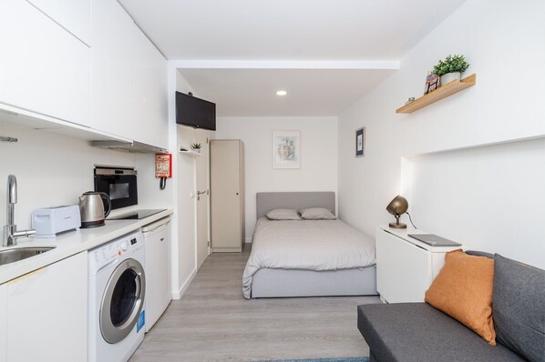 Cozy retreat with a kitchenette, comfortable bed, and a bedside table.