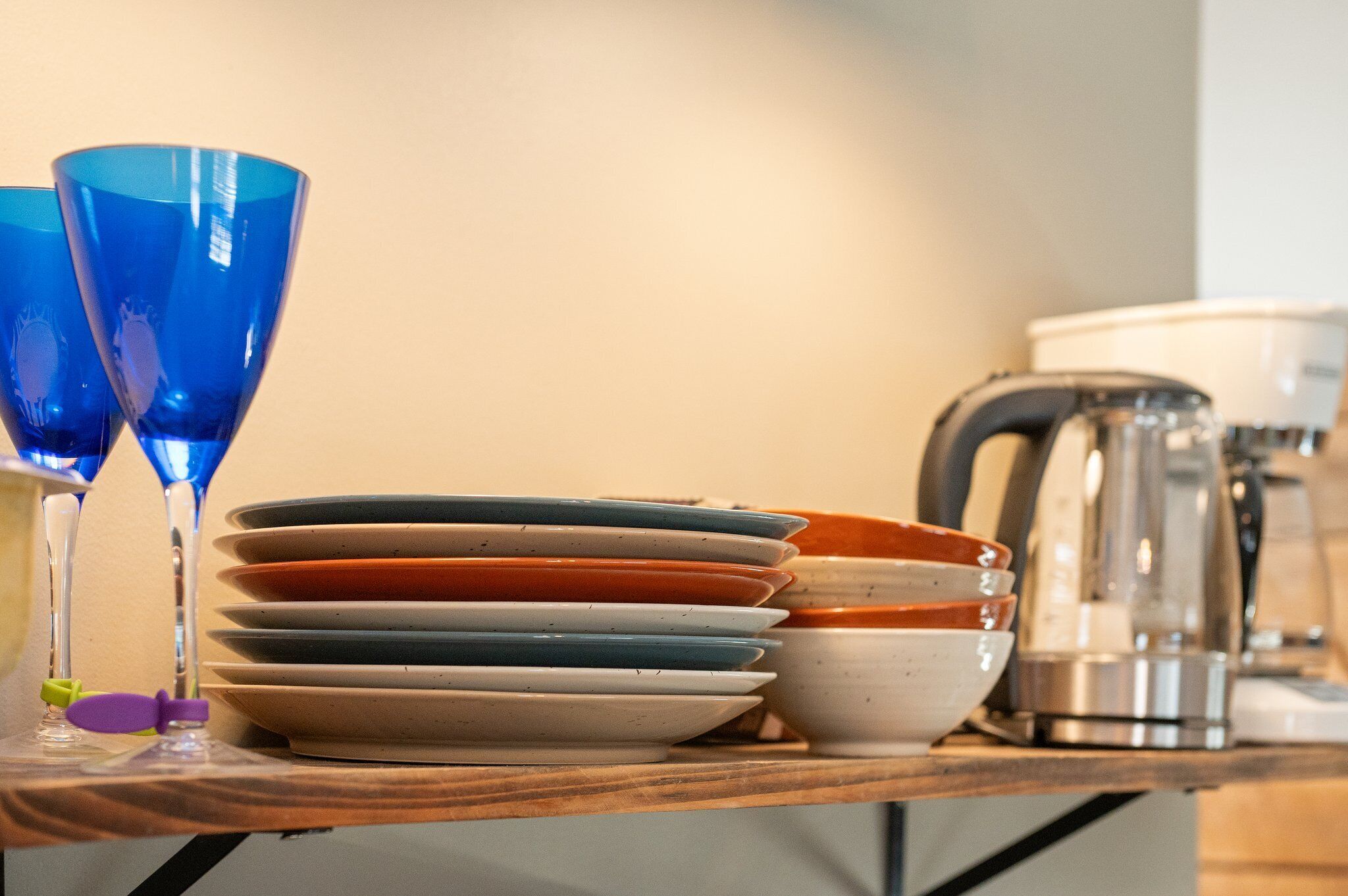 A stack of plates and glasses on a wooden table.