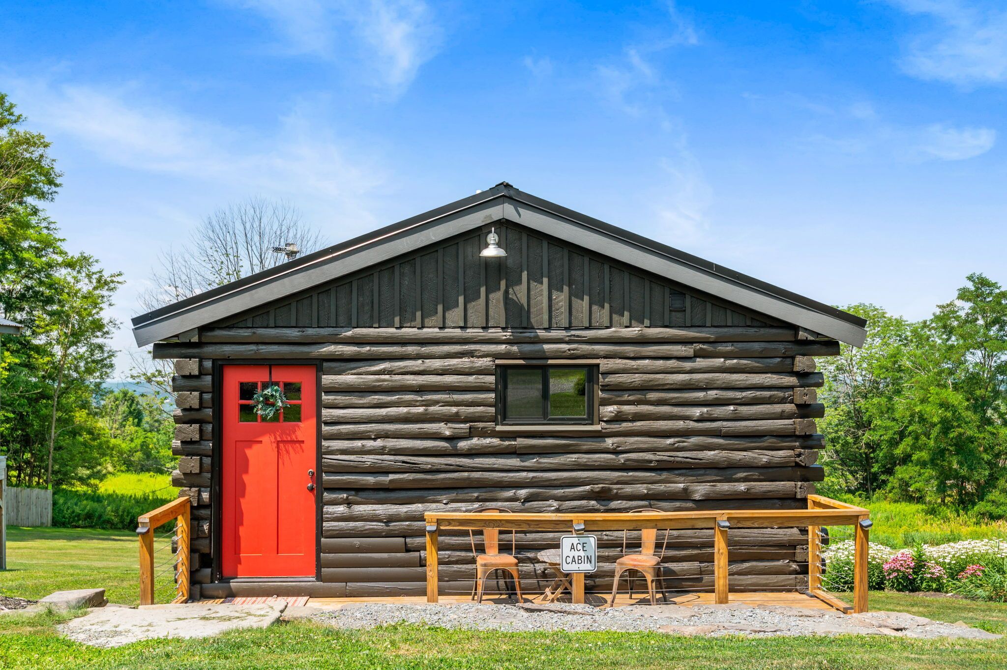 A log cabin with a red door, a small window, and a sign that reads "ACE CABIN."