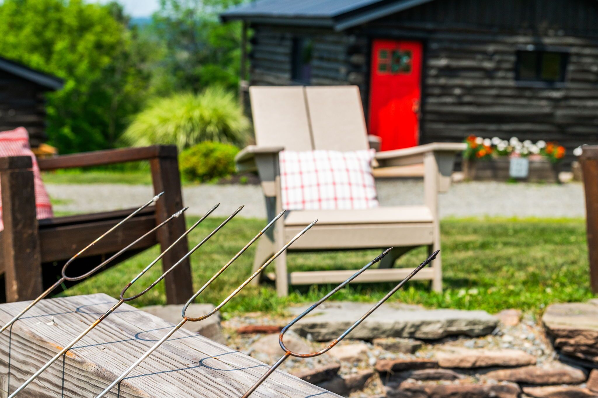 Un rustico chalet in legno con una porta rossa, una panca di legno e una sedia con una tovaglia a quadri.