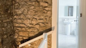 A stone wall and a white door leading to a bathroom with a sink and mirror.