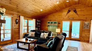 L’intérieur d’une cabane en rondins, avec un canapé en cuir, une table basse et une cheminée.