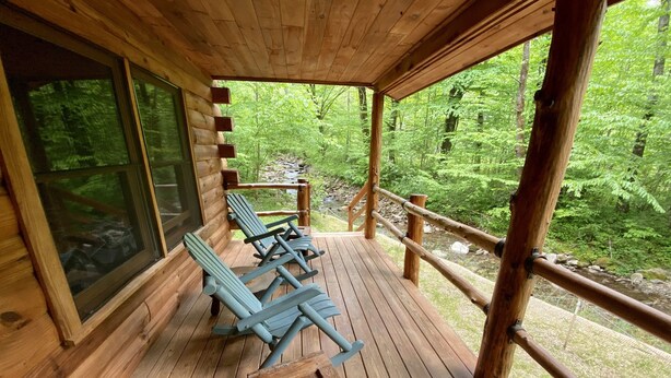 Une terrasse en bois avec des chaises longues et une petite table, donnant sur une zone boisée.