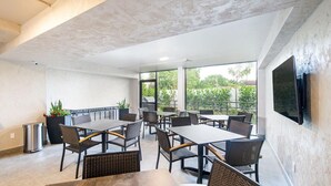 A modern outdoor dining area with multiple tables and chairs, a trash bin, and potted plants. - Wiggins Pass Chalet (Naples)