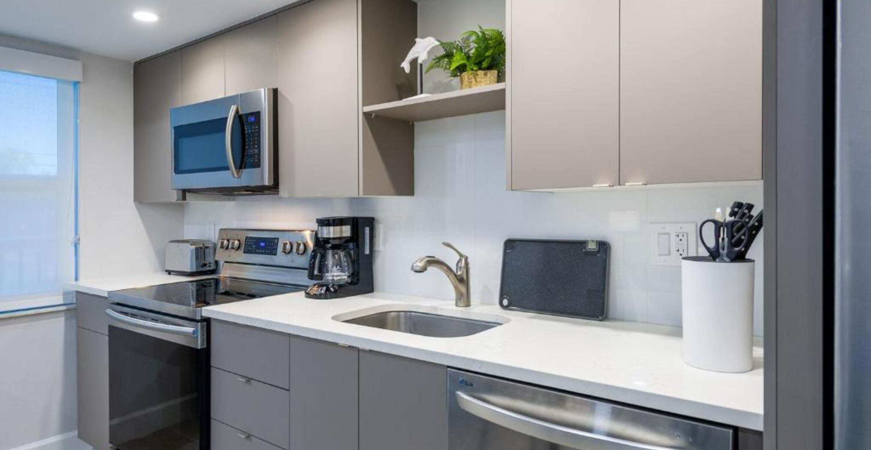 A modern kitchen with stainless steel appliances, a built-in oven, a coffee maker, and a sink.