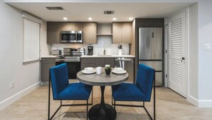 A modern kitchen with built-in appliances, a dining area with blue chairs, and a refrigerator. - Wiggins Pass Chalet (Naples)