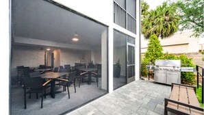 An outdoor patio with a dining area, a grill, and a large sliding glass door leading to an interior space. - Wiggins Pass Chalet (Naples)