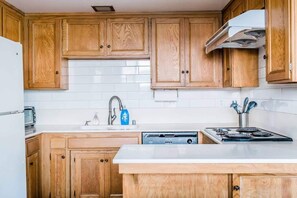 A kitchen with wooden cabinets, a white countertop, a dishwasher, a stove, and a microwave.