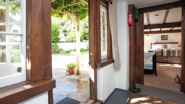 Une pièce aux murs en bois, avec un lit, une petite table et une fenêtre donnant sur un jardin.