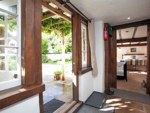 A wooden-framed room with a bed, a small table, and a window overlooking a garden. - 2 bedroom accommodation in Upexe, near Exeter (Upexe, near Exeter)