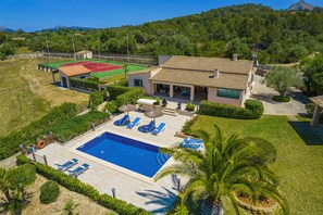 Une villa dotée d’une piscine, d’un espace salon extérieur et d’un court de tennis.