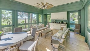 A spacious sunroom with a large dining table, comfortable seating, and a kitchen area.
