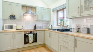 Een moderne keuken met lichte kastjes, een magnetron, een broodrooster, een spoelbak en een raam met uitzicht op de omgeving.